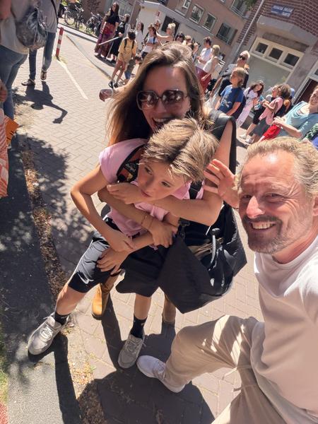 A family of three captures a joyful selfie on a bright, sunny day on Nieuwe Batavierstraat, Uilenburg, Amsterdam